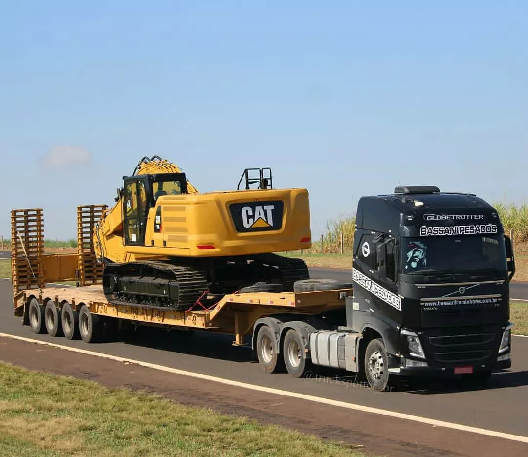 Excavadora amarilla asegurada sobre plataforma cama baja para transporte de carga sobredimensionada